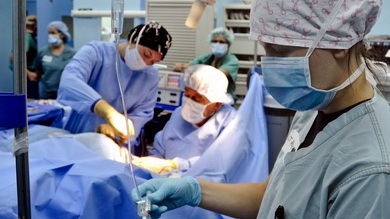 Na sali operacyjnej podczas operacji pielęgniarka trzyma kroplówkę